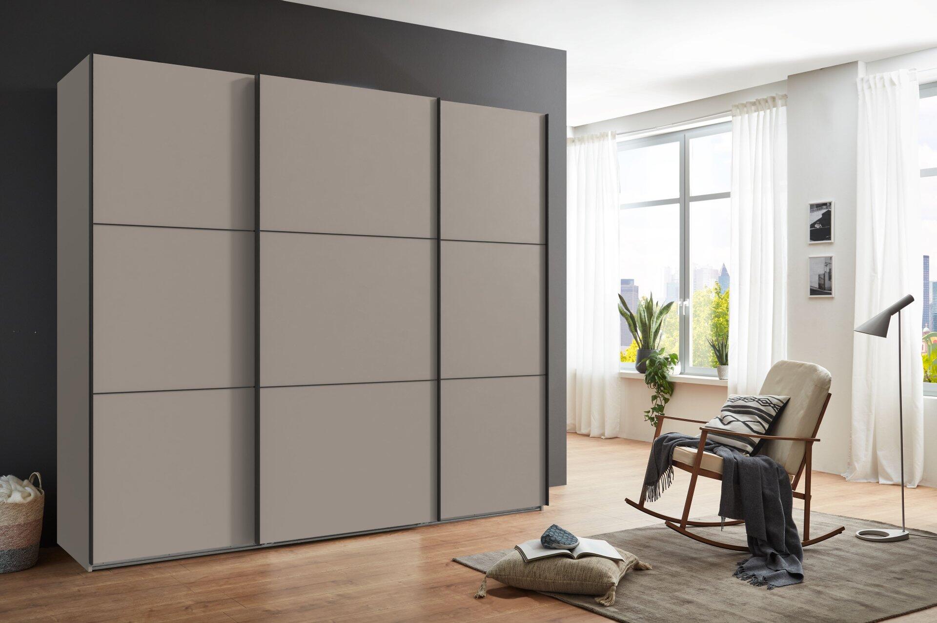 Schwebetürenschrank Indiana A in Saharagrau mit glatten Türen und vertikalen Linien, dargestellt aus einer frontalen, leicht seitlichen Perspektive.