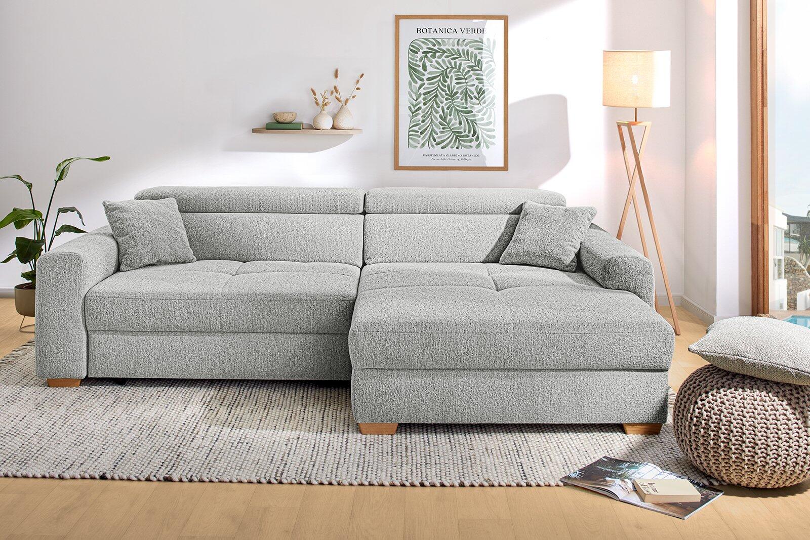 Graues Wohnzimmer Sofa mit Ottomane, die als Fußhocker oder Sitzflächenverlängerung genutzt werden kann, aus der Seitenperspektive fotografiert.