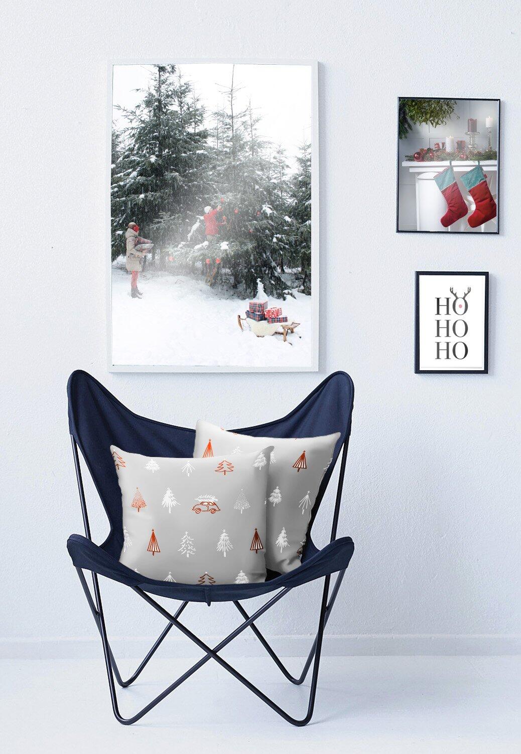 Schaukelstuhl mit dunkelblauem Kissen, das weihnachtliche Motive wie Tannenbäume, einen Schlitten und die Schriftzüge "Ho Ho Ho" zeigt.