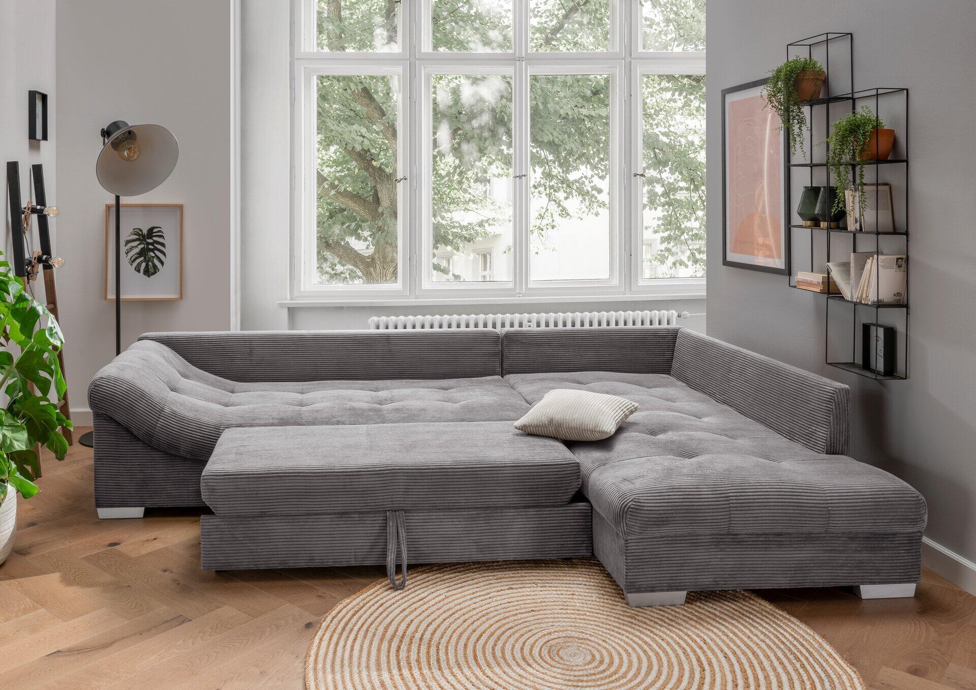 Ecksofa Alvito im ¾-Winkel mit Cordbezug und großzügigen Kissen, integriert in ein helles Wohnzimmer mit Teppich und Fenstern im Hintergrund.