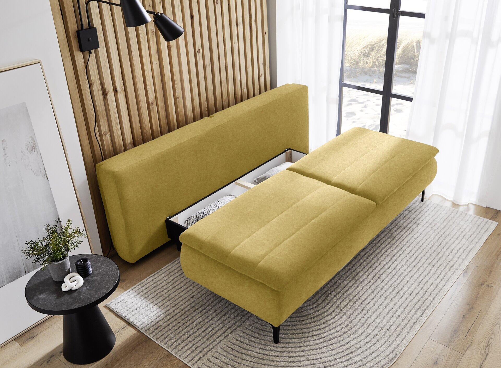 Gelb-grünes Boxspringsofa "Melly" mit geöffneter Schlaffunktion und freiliegendem Bettkasten, dargestellt in einer seitlichen Perspektive in einem stilvollen Wohnambiente.