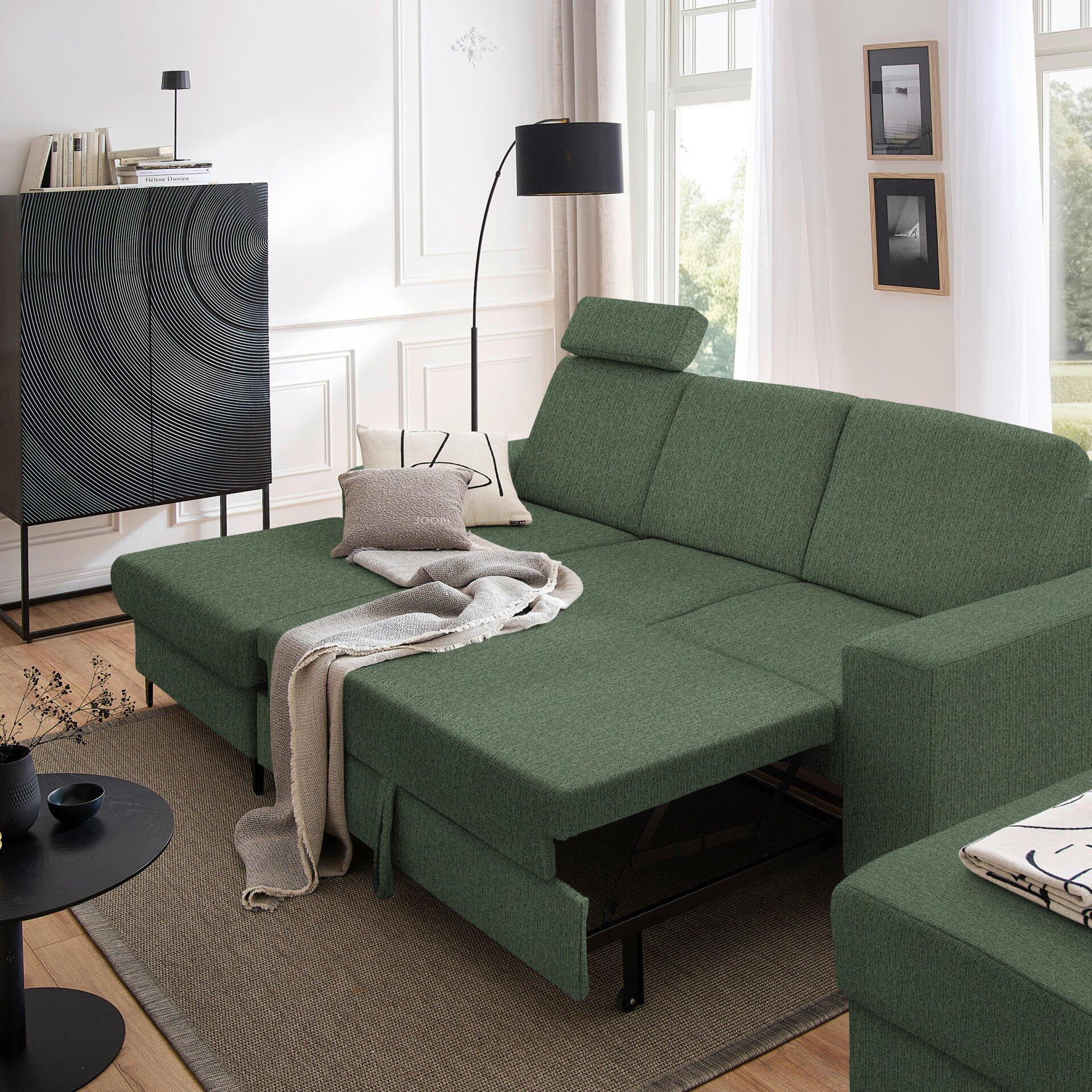 Grünes Ecksofa Balina mit ausgezogenen Bett und hochgeklappter Schlafmechanik, eingebettet in ein modernes Wohnzimmer.