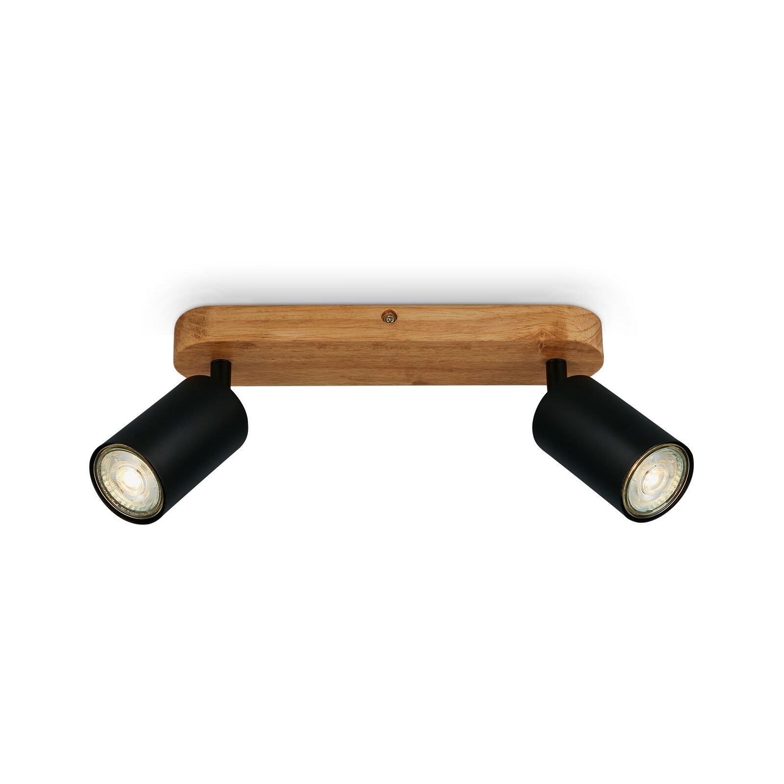 Moderne Wandlampe Spot Kullig mit zwei schwarzen, zylindrischen Leuchtenköpfen auf einem hellen Holzarm.