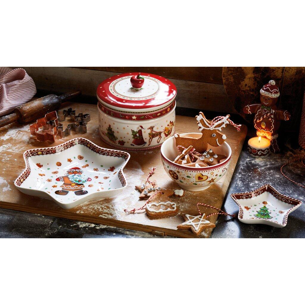 Villeroy & Boch Gebäckdose Winter Bakery mit rotem Deckel und Kirsch-Applikation, präsentiert auf einer festlich dekorierten Holzplatte mit Lebkuchenformen und weihnachtlichen Motiven.
