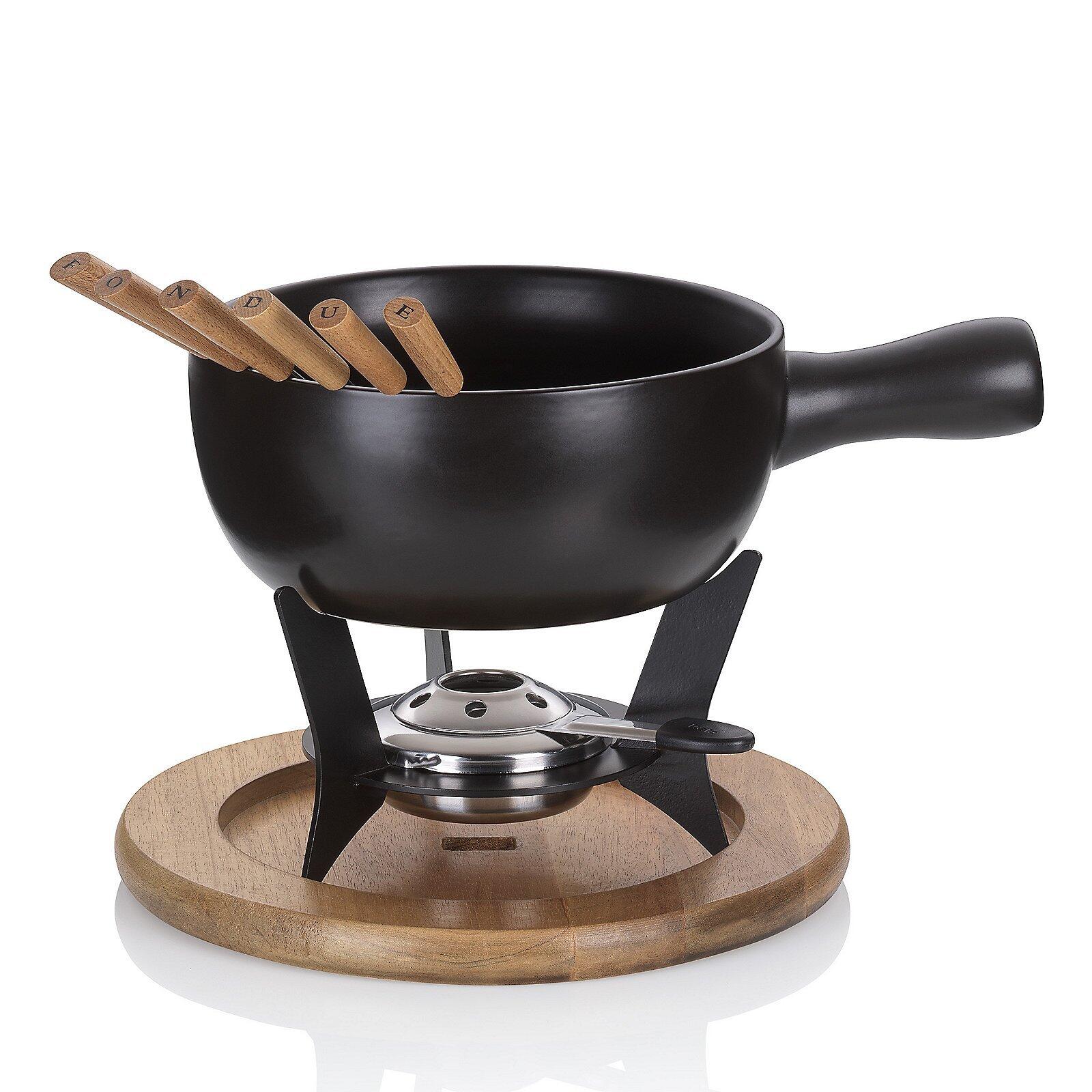Fondue-Set "Country" mit schwarzem Topf, Holzspießen und Heizvorrichtung auf rundem Holzbrett.