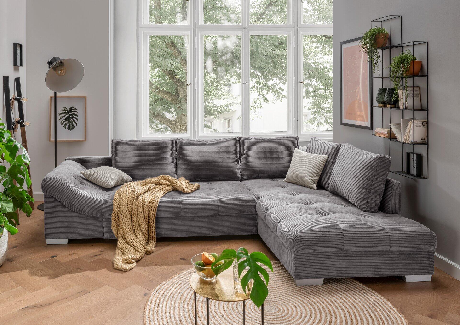 Ecksofa Alvito in Grau mit L-Form, geriffelter Oberfläche und hellen Kissen, fotografiert aus erhöhter Perspektive in einem stilvoll eingerichteten Wohnzimmer.