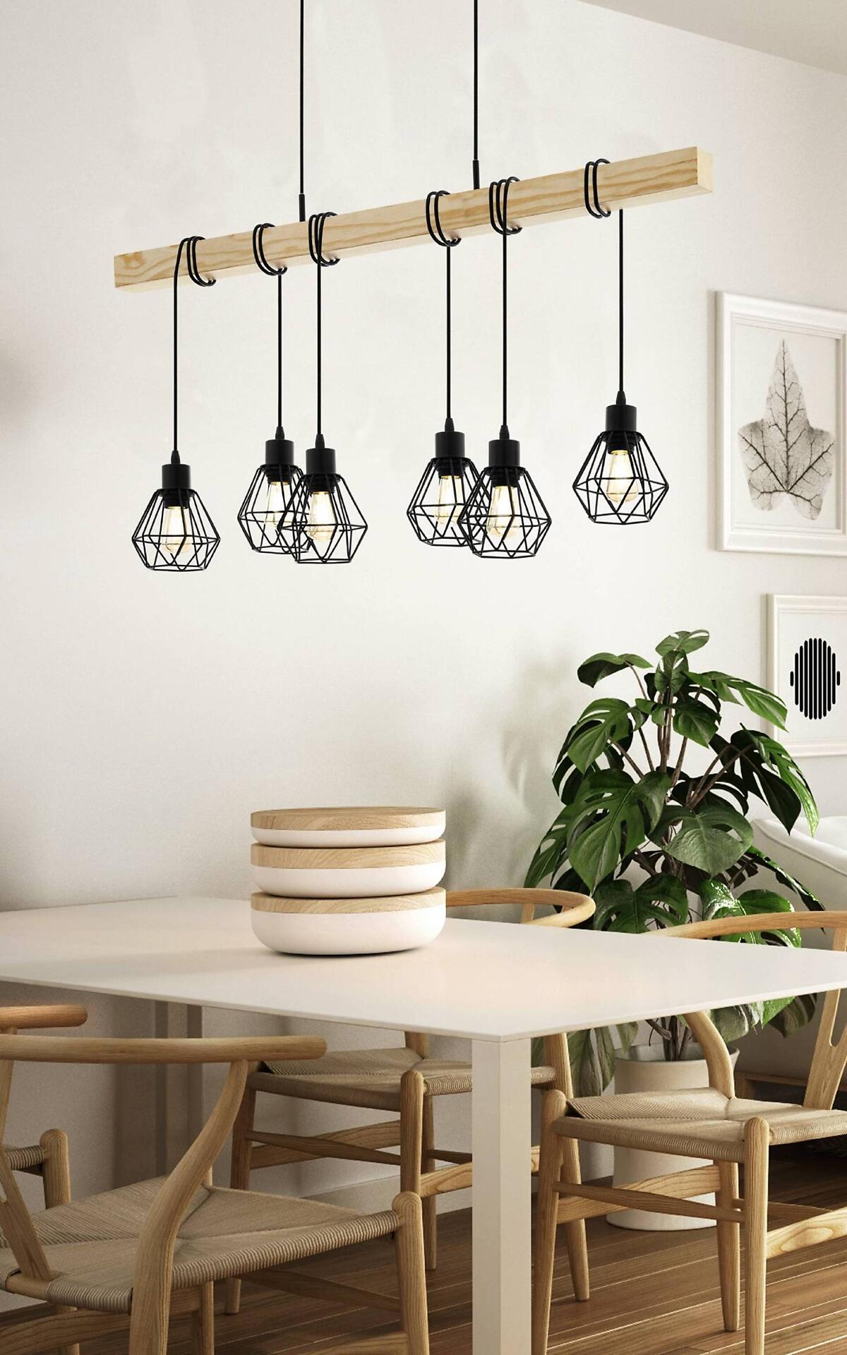 Pendelleuchte Townshend 5 mit fünf schwarzen Metall-Käfiglampen, die an einem Holzstab hängen und über einem Esstisch warmes Licht ausstrahlen.