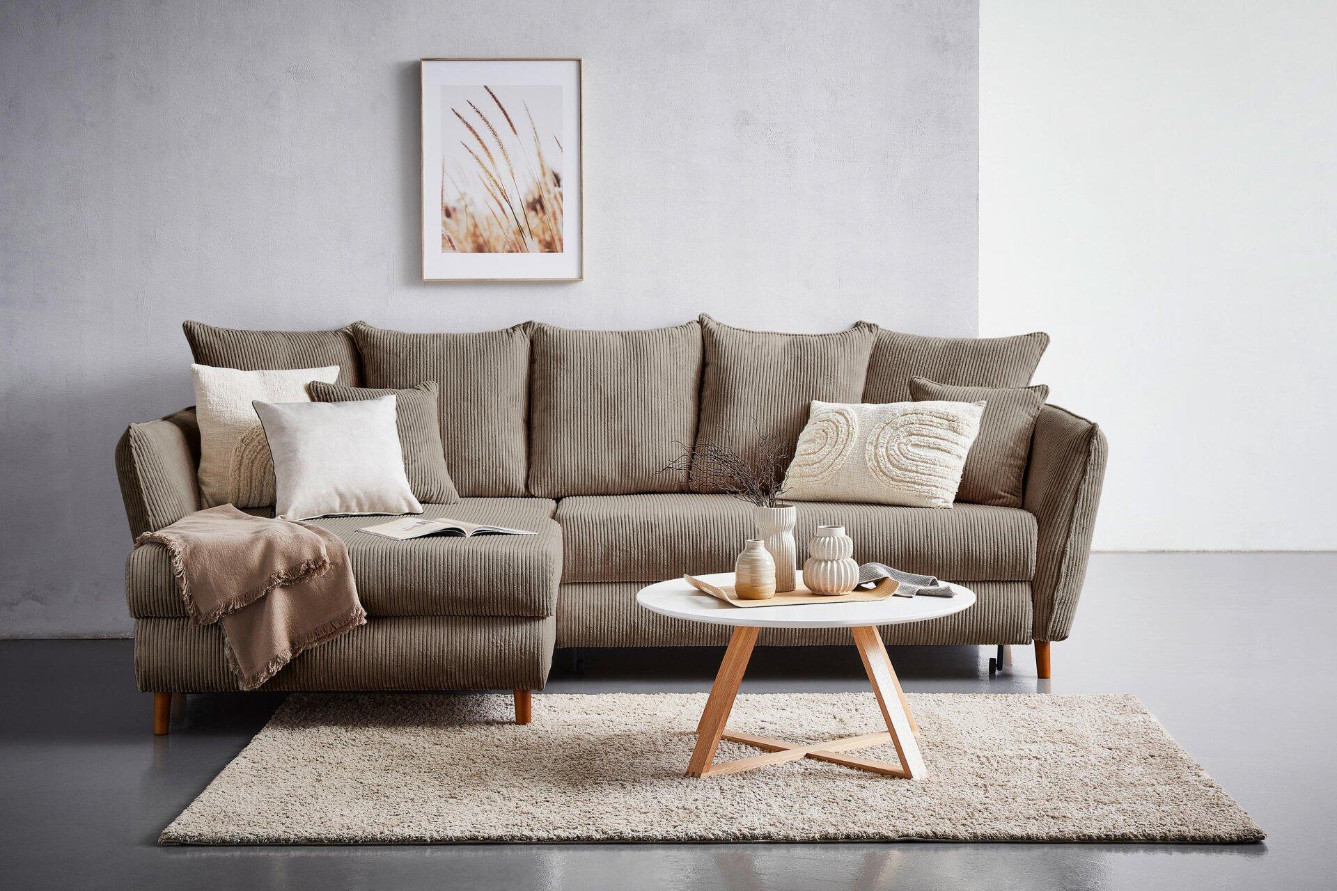 Ecksofa Santana mit Cordbezug in L-Form, ausgestattet mit Zierkissen, Rückenkissen und Bettkasten, aus einer frontalen Perspektive im Wohnzimmerambiente.