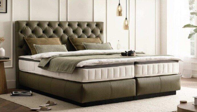 Boxspringbett Graz mit gepolstertem Kopfteil in Schachbrettoptik und mehreren Liegezonen, präsentiert in einem stilvollen Schlafzimmer.