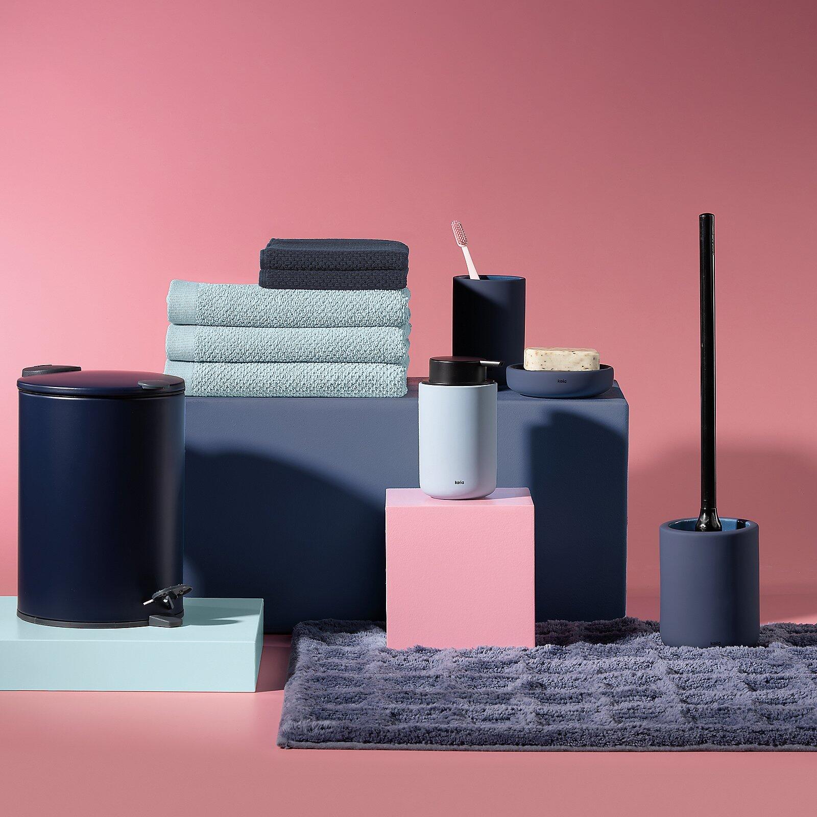 Duschtuch Lavinia, grau, in einer Badezimmer-Szene mit Handtüchern und Accessoires, leicht erhöhte Perspektive.