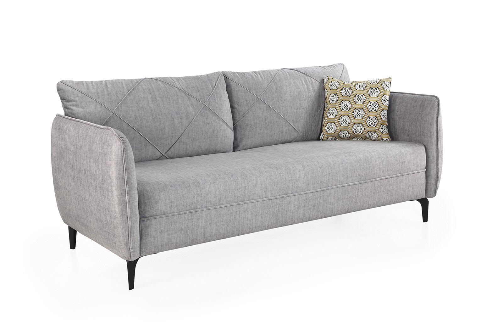 Graues 3-Sitzer Sofa Novara mit abgerundeten Armlehnen, diagonal gestepptem Rücken und gelb-grauem Dekor Kissen auf der Sitzfläche, stehend auf schwarzen Füßen.