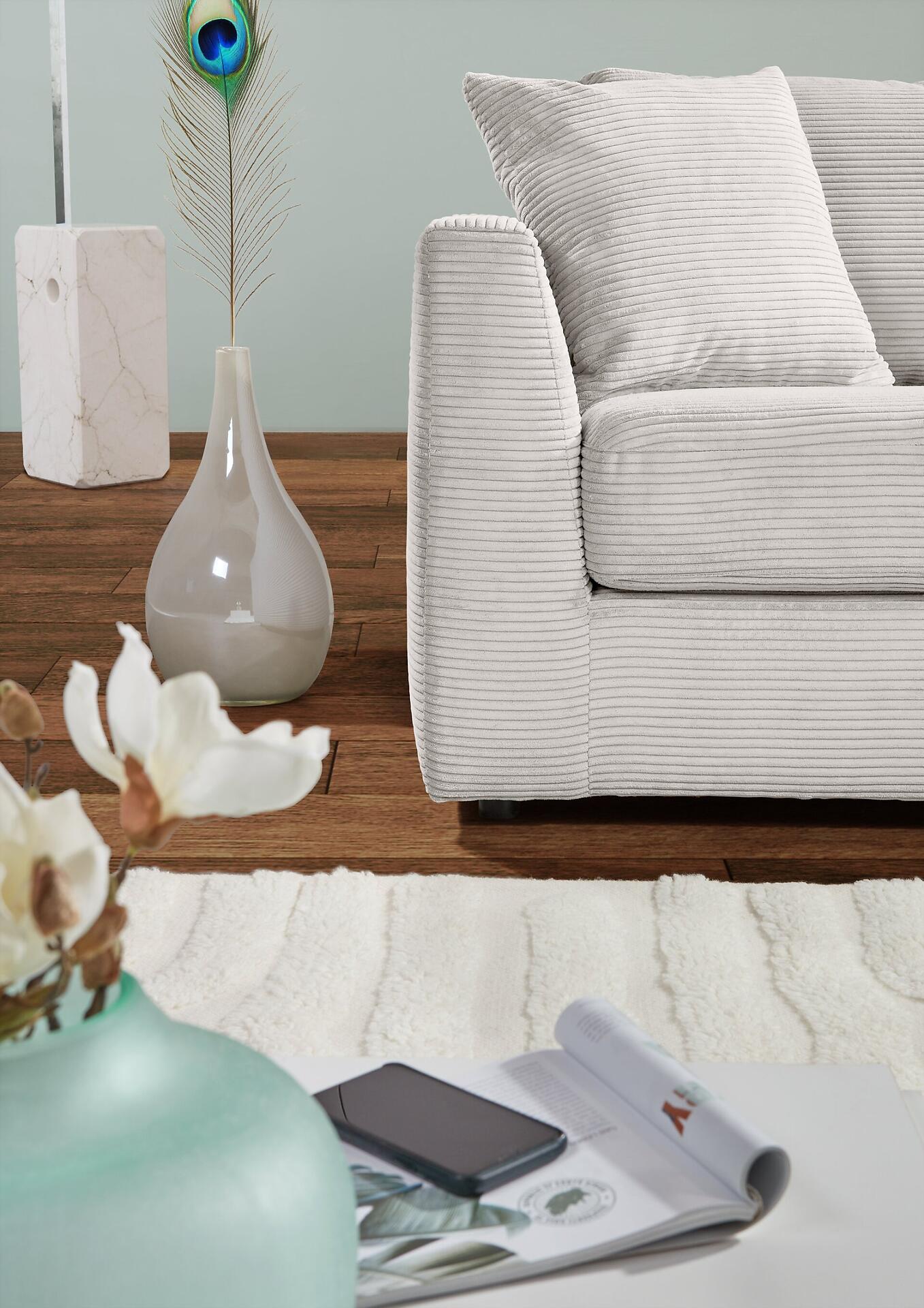 Helle Cordsofa mit vertikaler Struktur und weichem Erscheinungsbild, leicht erhöhte Perspektive zeigt die einladende Textur und Details der Innenraumgestaltung.