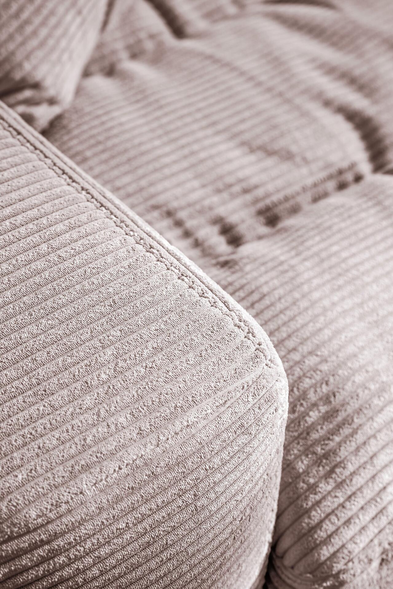 Detailaufnahme des hellgrauen Cordvelours-Bezugs der Polstergarnitur Badia, die die weiche Textur und die abgerundete Kante für einen komfortablen Sitz betont.