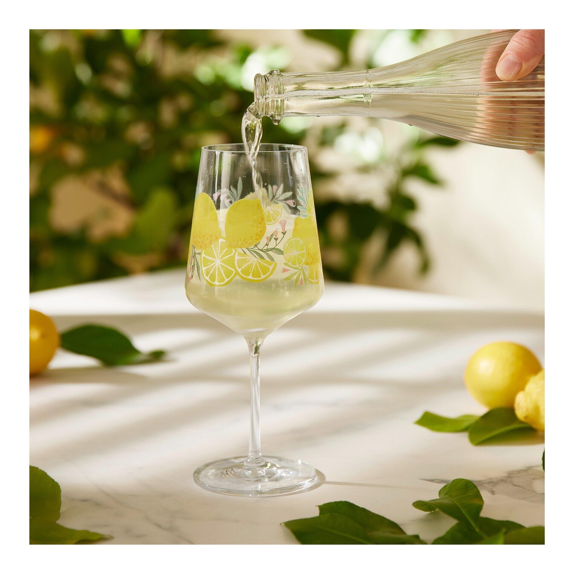 Aperitifglas-Set mit einem konisch zulaufenden Glas aus Vogelperspektive, in das ein gelbes Getränk gegossen wird, mit Zitronenmotiv und in Geschenkbox verpackt.