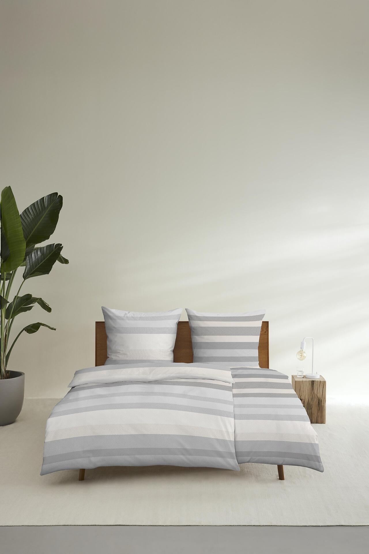 s.Oliver Renforcébettwäsche in grau und weiß mit vertikalen Streifen auf einem Bett, frontal fotografiert.