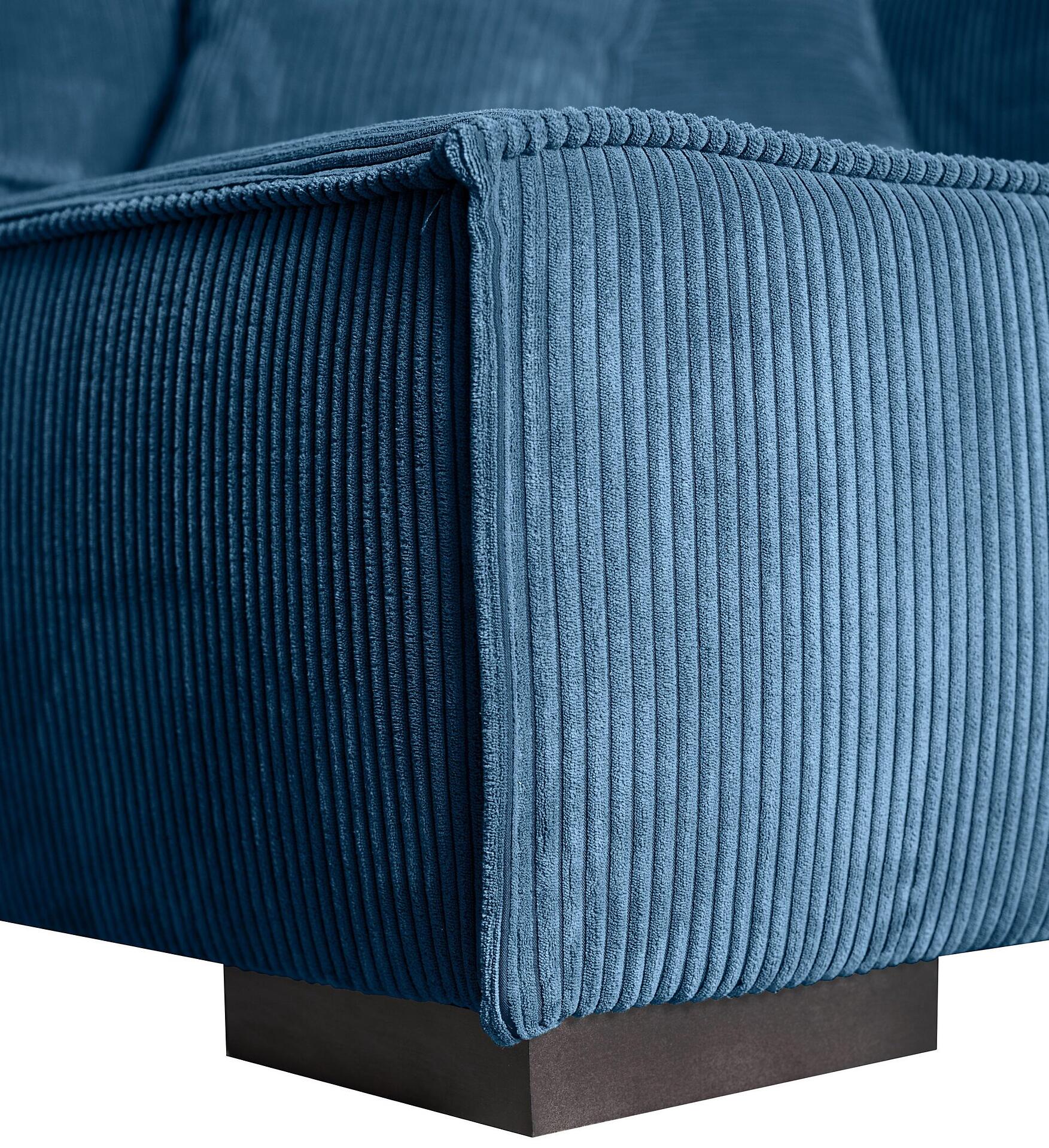 Detailaufnahme der Armlehne des Ecksofas Mango mit blaugrünem Samtstoff und vertikaler Cordstruktur auf einem dunkelbraunen Holzfuß.