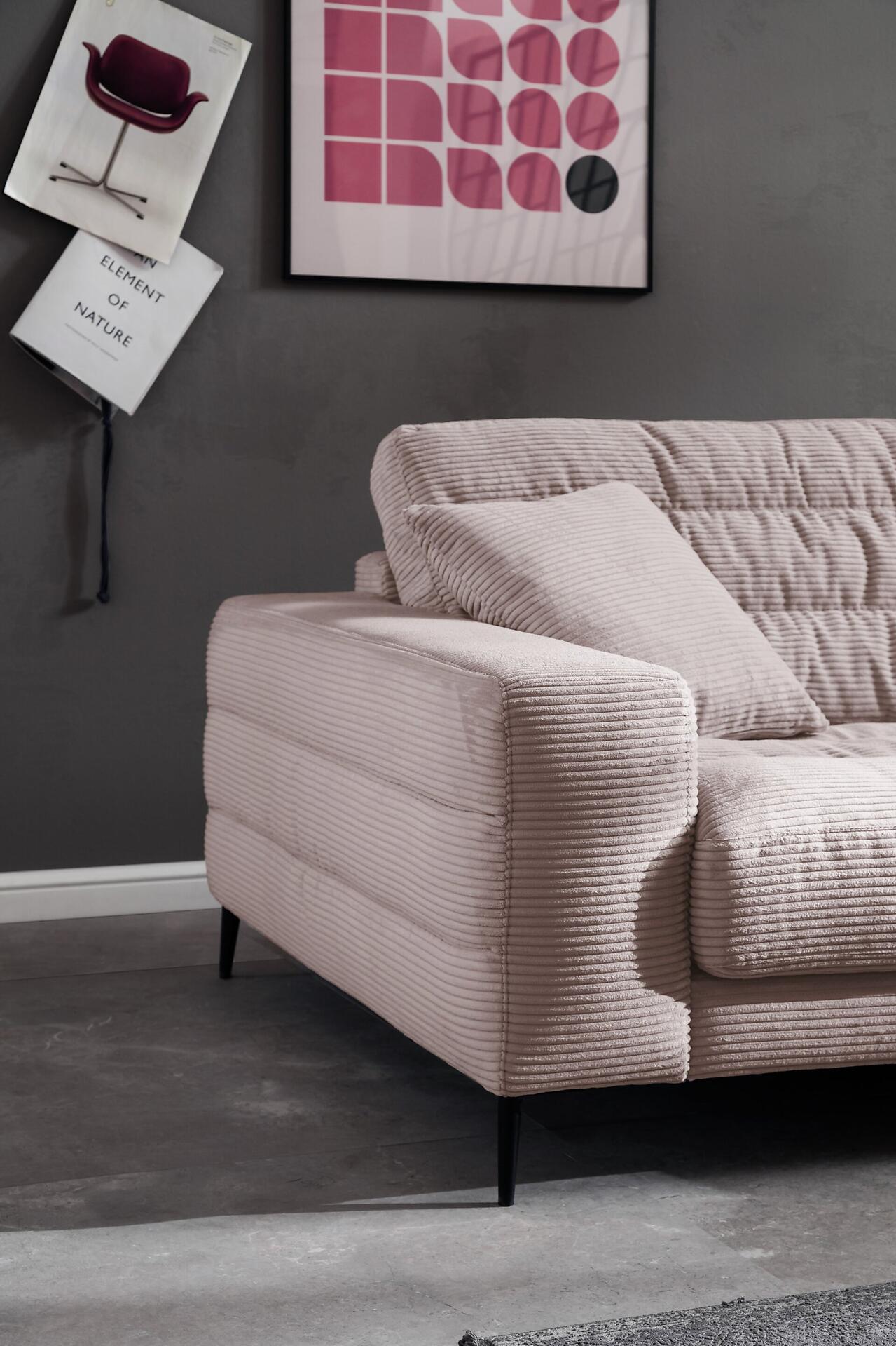 Nahaufnahme eines pinkfarbenen Cordsofas der Polstergarnitur Badia mit Strukturstoff und niedrigem Sitz, das einen modernen Wohnstil betont.