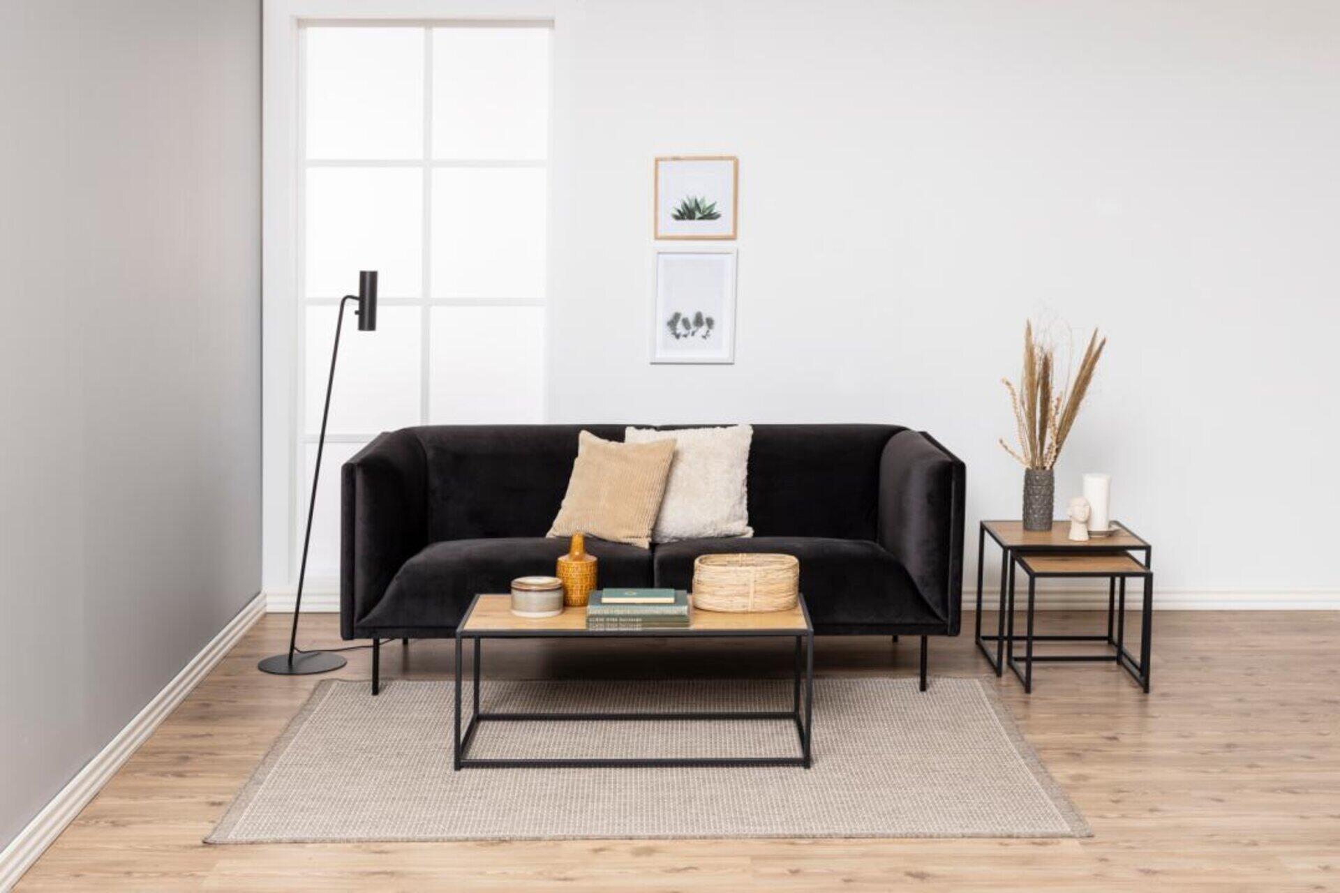 Couchtisch Seaford mit schwarzem Metallgestell und Holzplatte, arrangiert vor einer bequemen Sofaecke in einem modernen Wohnzimmer.