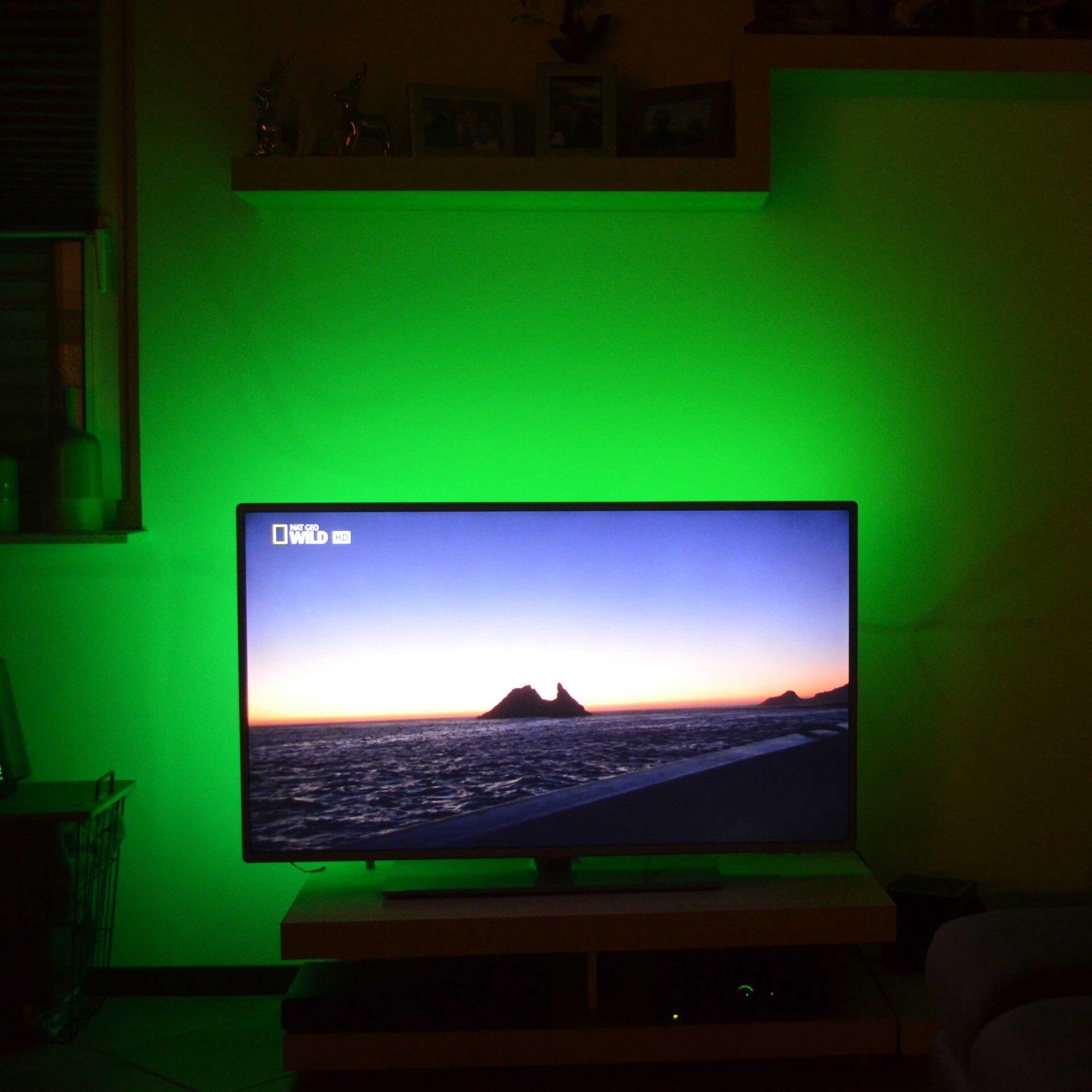 LED Band BRILO für TV mit stimmungsvoller Hintergrundbeleuchtung, dargestellt vor einem Fernseher mit Sonnenuntergang-Bildschirm.