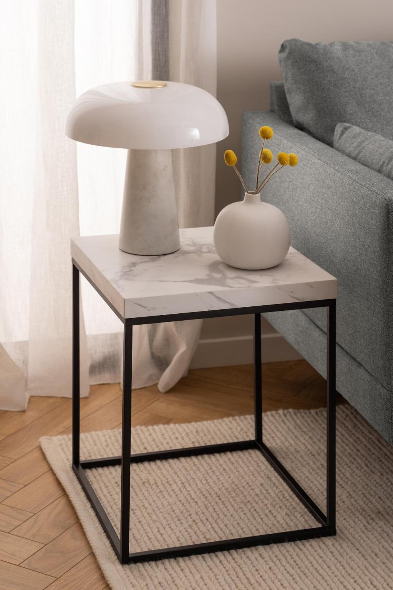 Beistelltisch Barossa mit Marmorplatte, schwarzem Metallgestell und integrierter Ablagefläche, detailliert gezeigt mit Tischlampe und Blumen auf der Oberfläche.