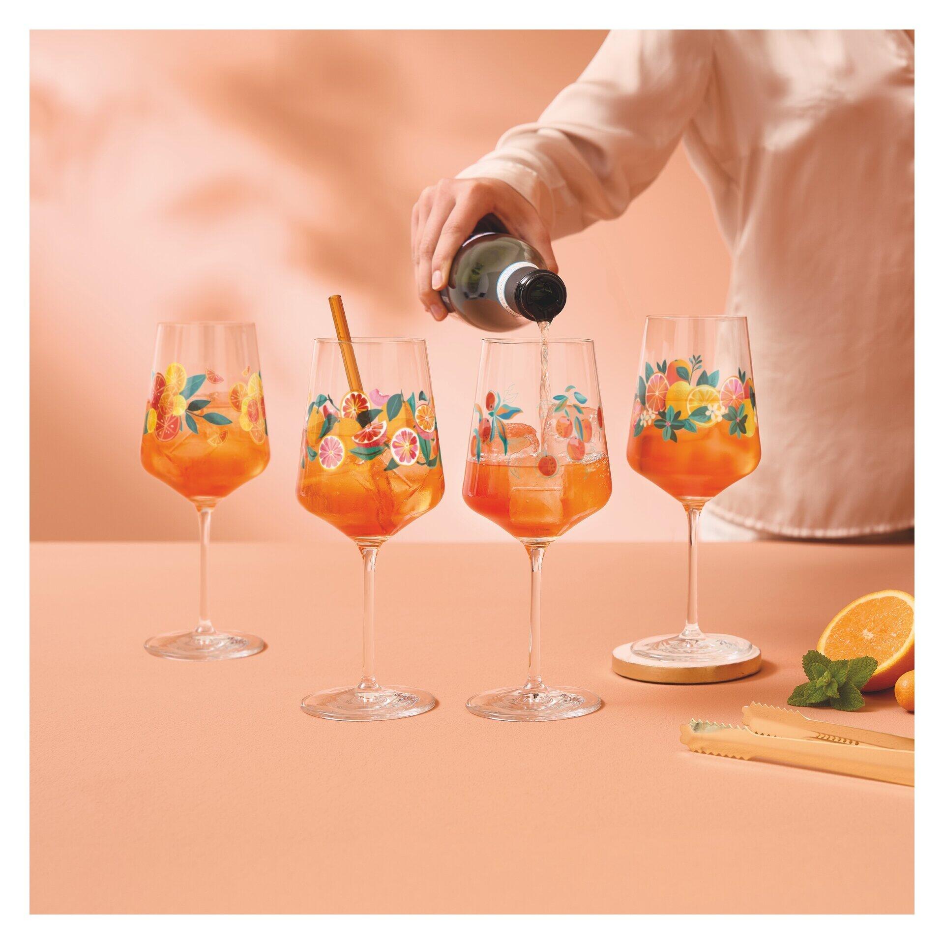 Nahaufnahme eines Aperitifglas-Sets, in dem ein Mann orangefarbenes Getränk mit Eiswürfeln und Orangenscheibe in ein mit floralem Muster versehenes Glas gießt.