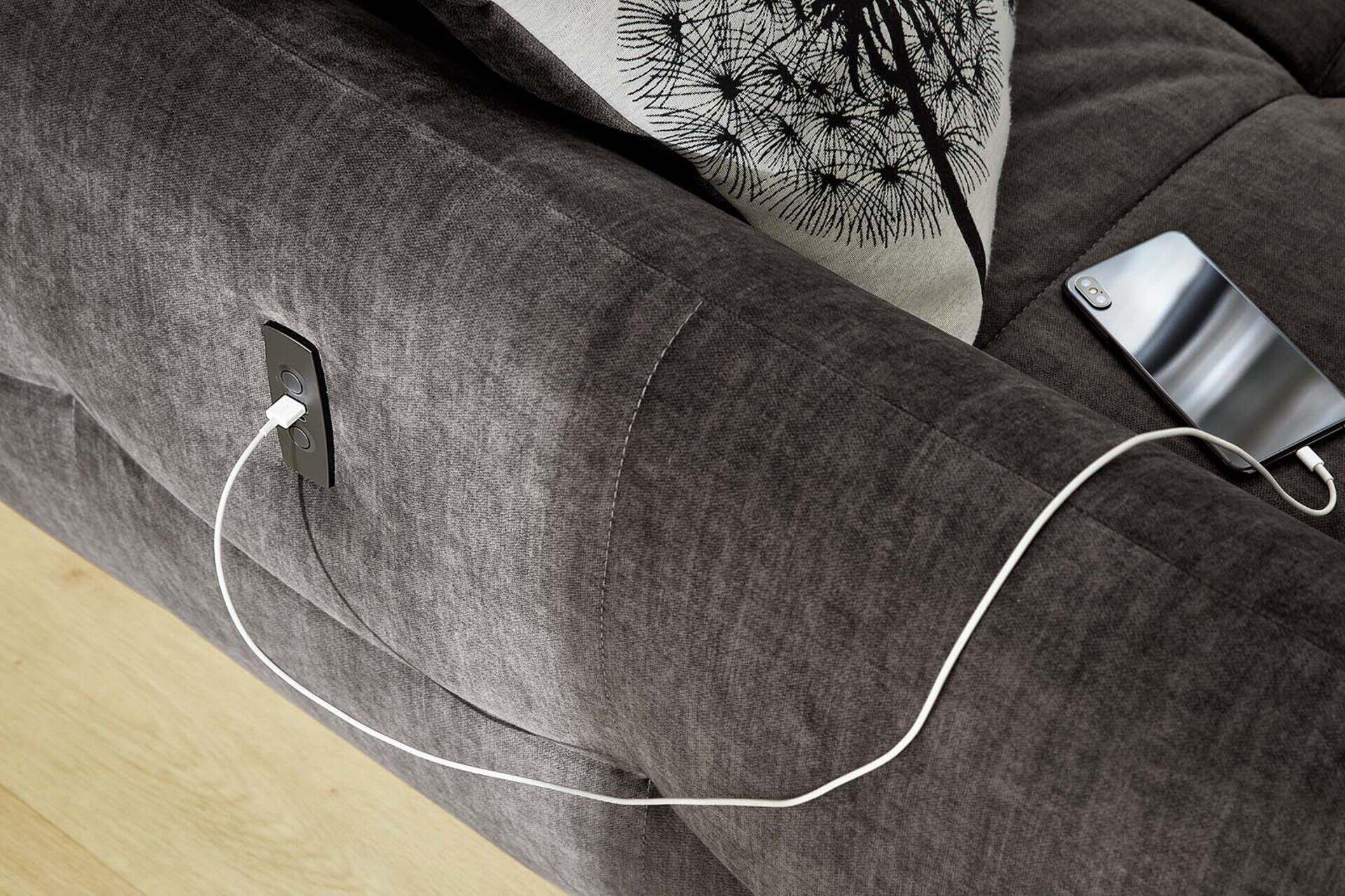 Detailaufnahme der Wohnlandschaft Zoom: Gestepptes Sofa mit integrierter Steckdose für das Aufladen eines Smartphones auf dem Armteil.