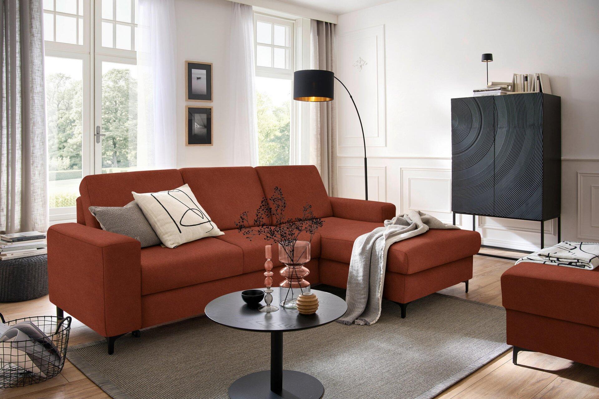 Ecksofa Balina in L-Form mit Winkelfüßen, Schlaffunktion und Bettkasten, dargestellt aus leicht erhöhter Perspektive in einem stilvollen Wohnzimmer.