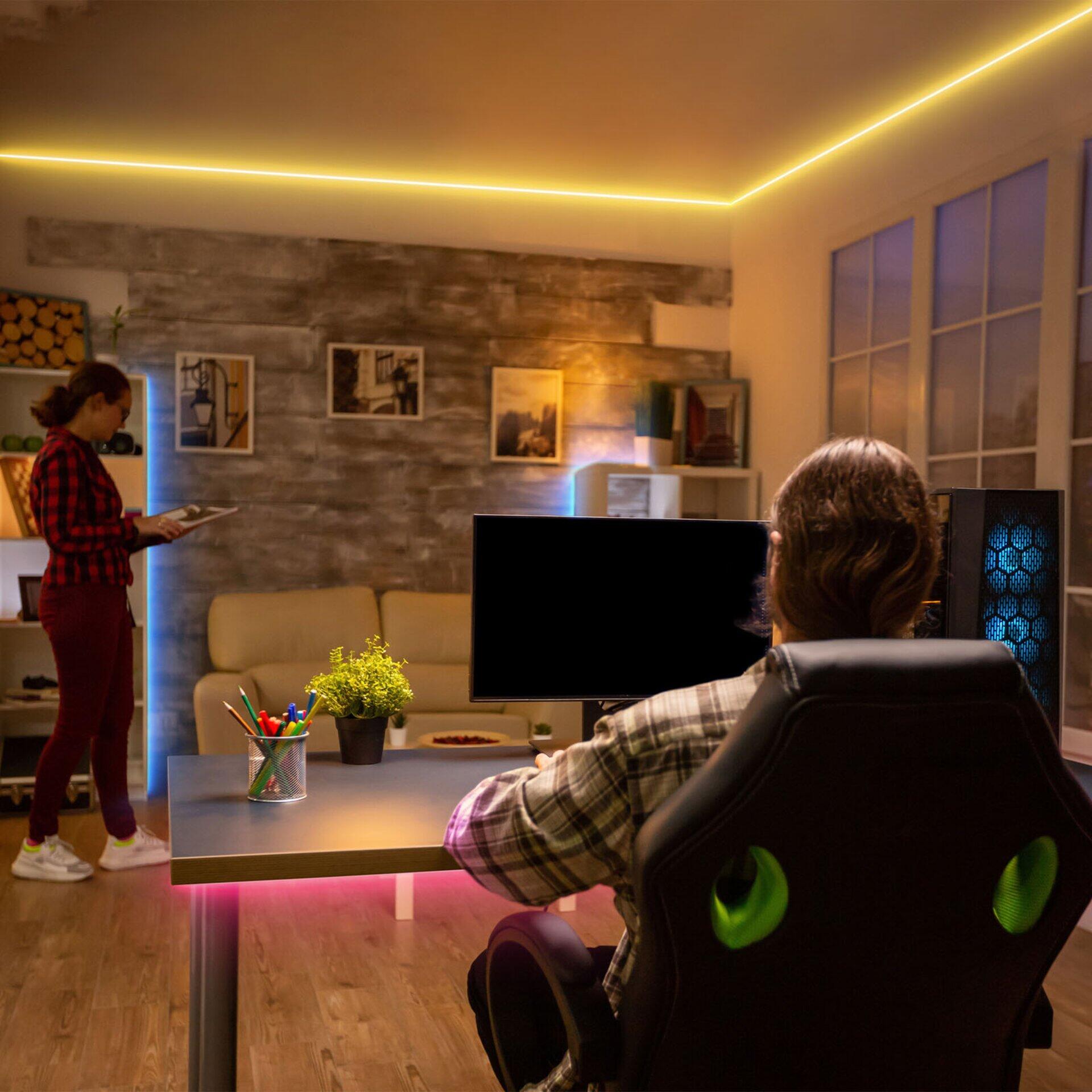 LED Band Magic, beleuchtet einen Gaming-Arbeitsbereich mit rotem und grünem Licht von oben, aus erhöhter Perspektive.