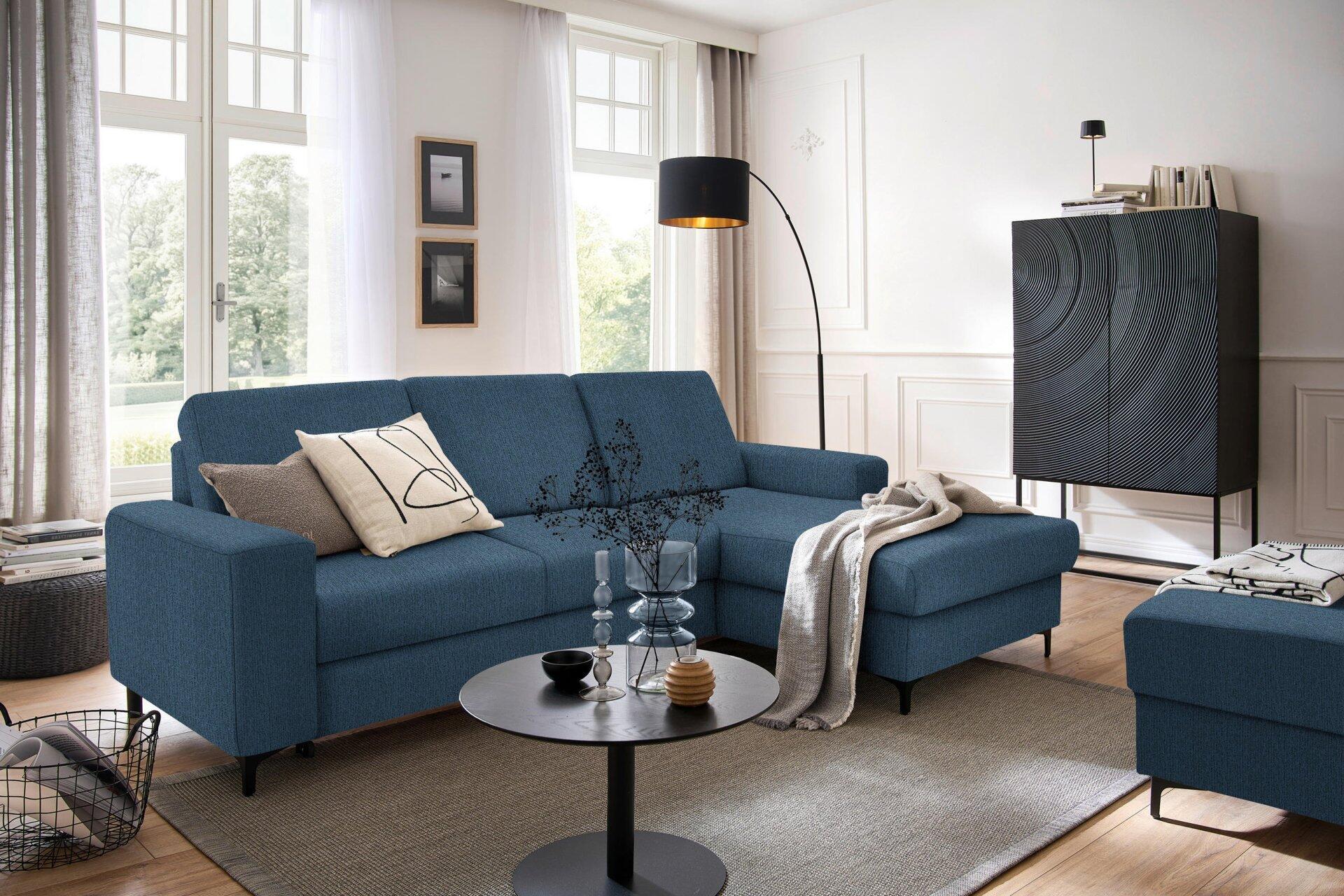 Dunkelblaue Eckcouch Balina mit Winkelfüßen, leicht seitliche Ansicht zeigt die geometrische Form und die ausgeklappte Schlaffunktion.