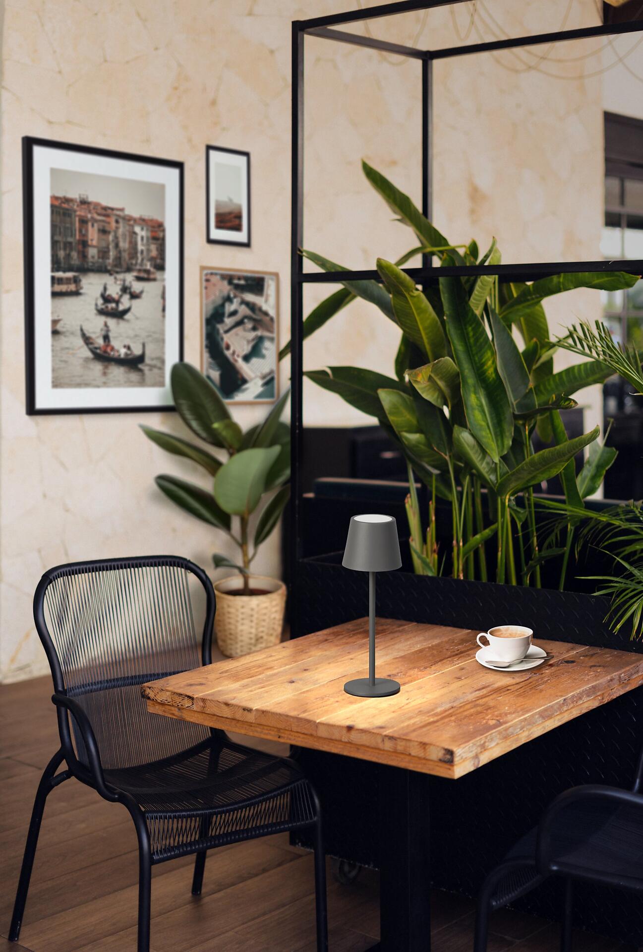 Tischleuchte Roxi mit Sensordimmer, dargestellt auf einem Holztisch mit Kaffeetasse und stilvollem Hintergrund.