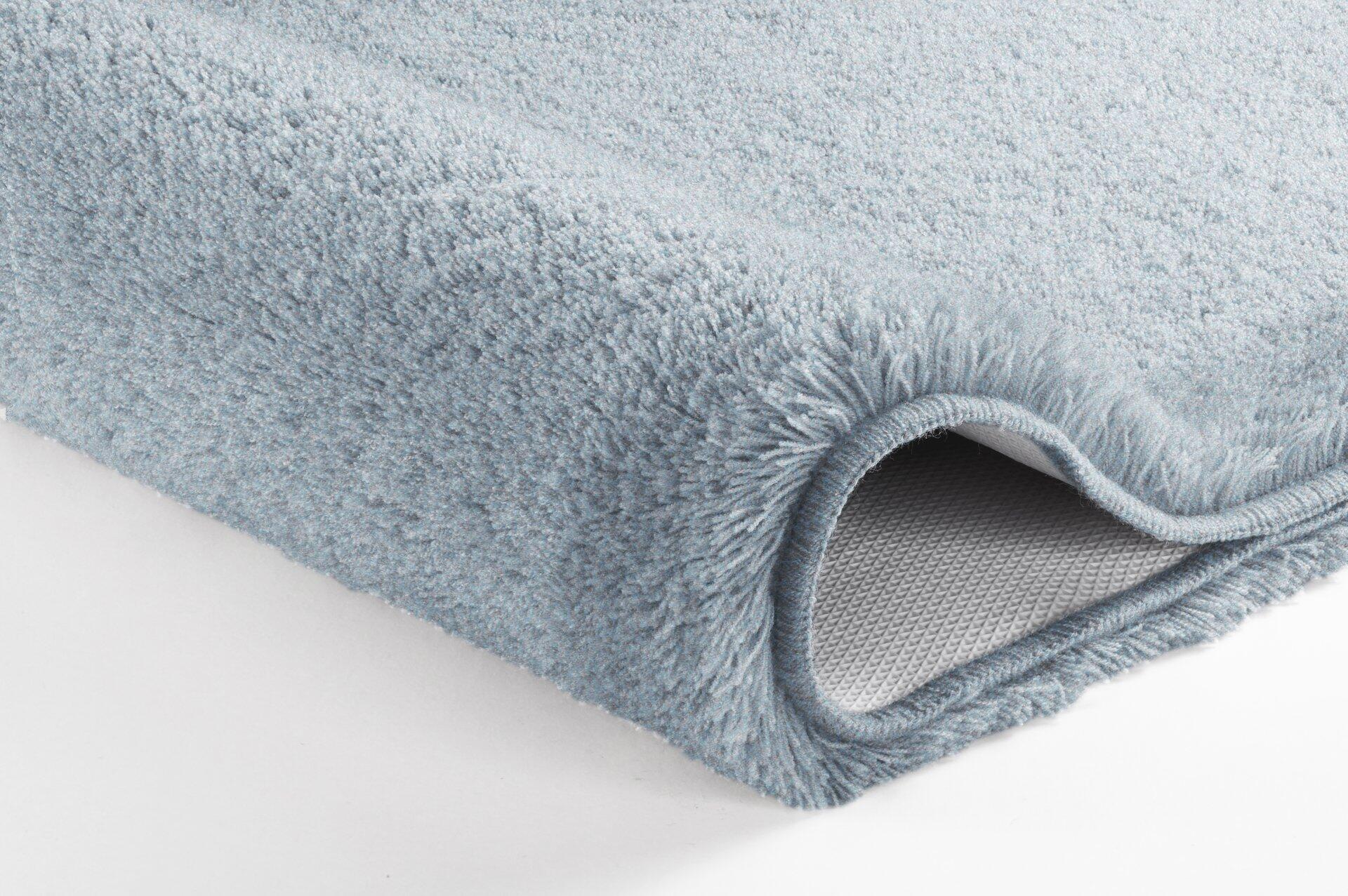 Relax Deckelbezug, Stahlblau: Detailaufnahme des flauschigen, hellblauen Teppichs mit hochgeklappter Ecke, die das strukturierte Rückseitengewebe zeigt.