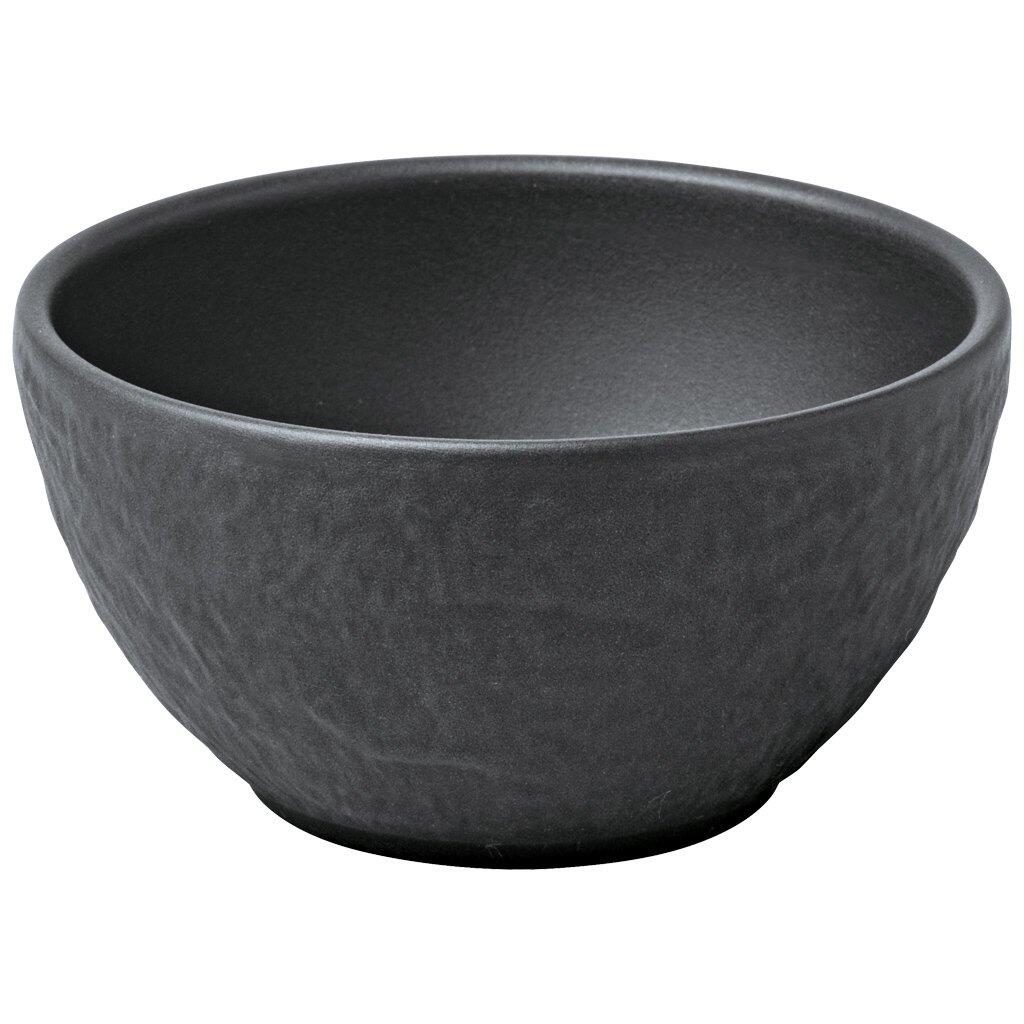 Schwarzes Dipschälchen Manufacture Rock von Villeroy & Boch mit gewellter, rustikaler Textur und glasiertem, mattem Finish, aus einer leicht seitlichen, unteren Perspektive.