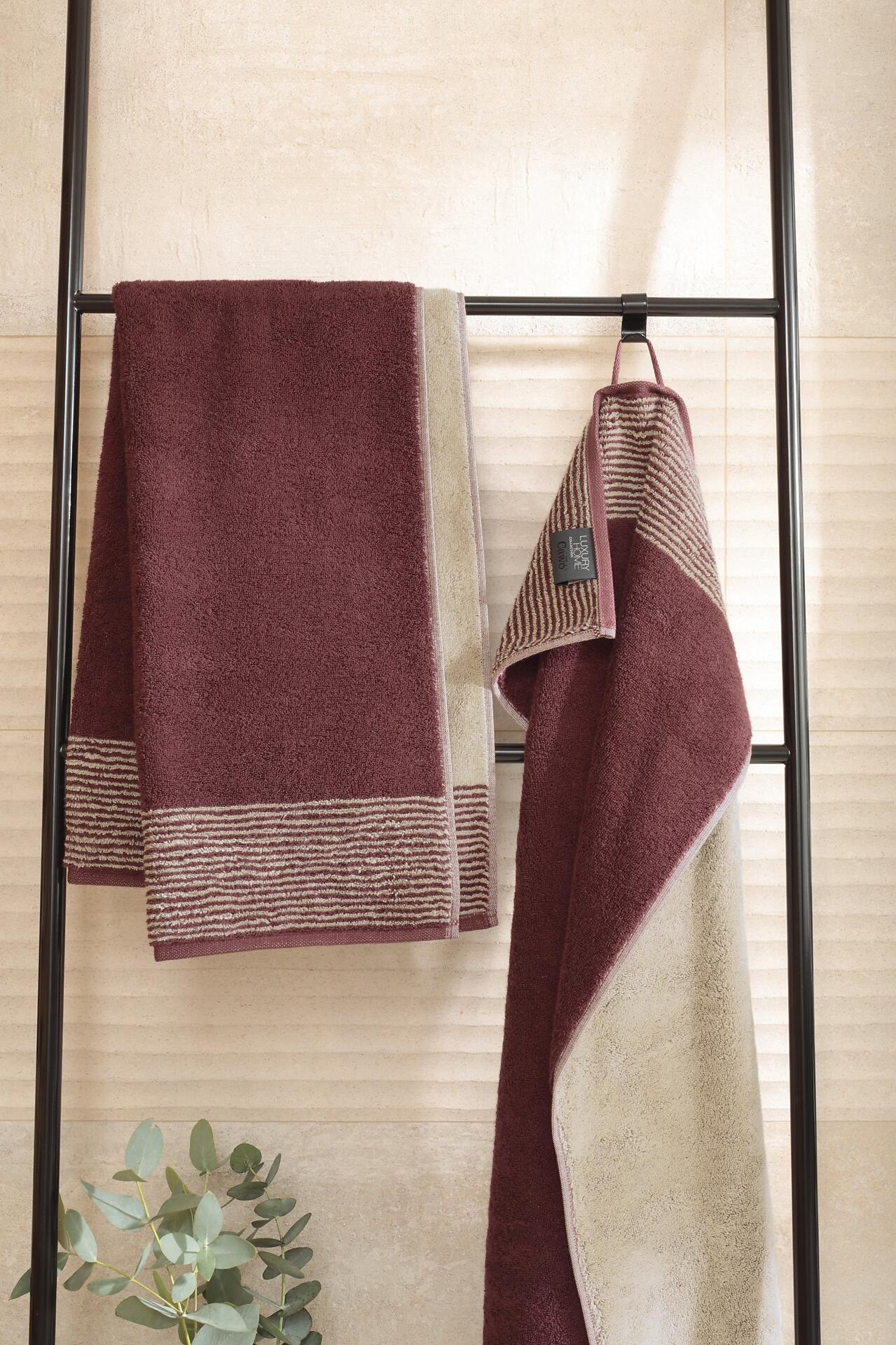 Gästetuch Two-Tone bordeaux, dunkel-lila und beige gestreift, flauschige Textur, an einem Wäscheständer hängend.