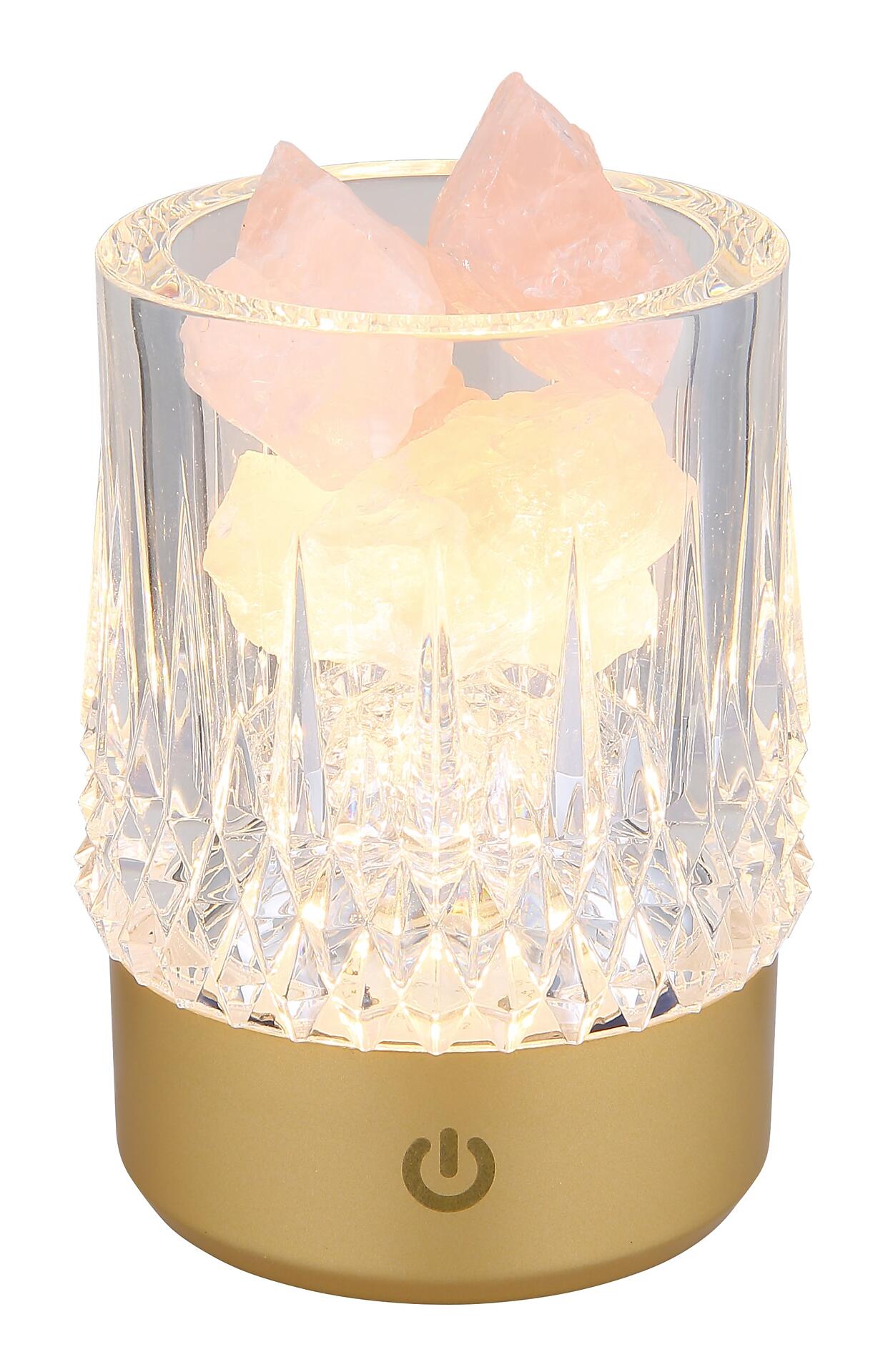 Steinsaltzlampe mit facettiertem Lampenkörper und rosa-orangefarbenen Steinsalzstücken auf goldenem Sockel mit Touch-Ein/Aus-Symbol.