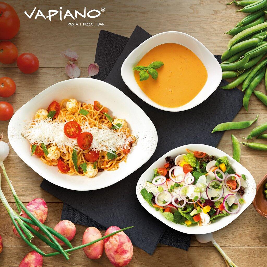 Schalen-Trio Vapiano: Zwei Teller mit Spaghetti und Salat, präsentiert auf einer Holzoberfläche, zeigt die ovalen, weißen Schalen im Kontext einer Mahlzeit für zwei Personen.