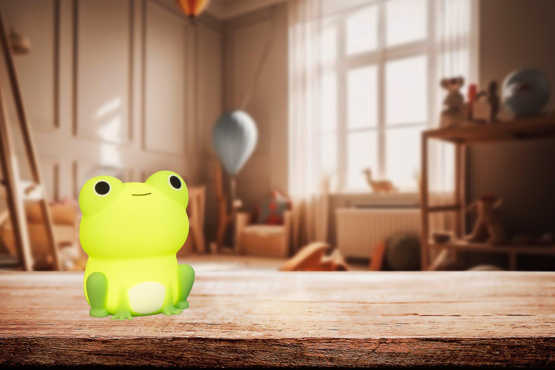 Tischleuchte Willi mit einem grünen, cartoonartigen Frosch-Design, dargestellt aus einer unteren Perspektive, die die RGB-Beleuchtung und den dekorativen Charakter der Leuchte hervorhebt.