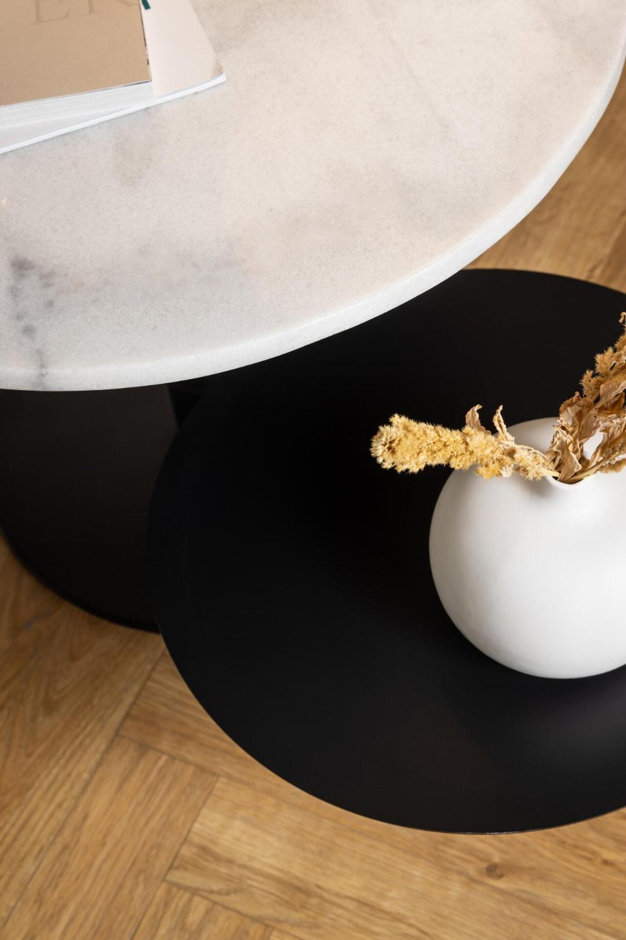 Detailaufnahme des Couchtischs Lahti mit Drehfunktion, der eine helle Marmorplatte mit dunklen Adern und ein matt schwarzes Metallgestell zeigt, wobei eine zweite, kleinere Tischplatte unter der oberen sichtbar ist.