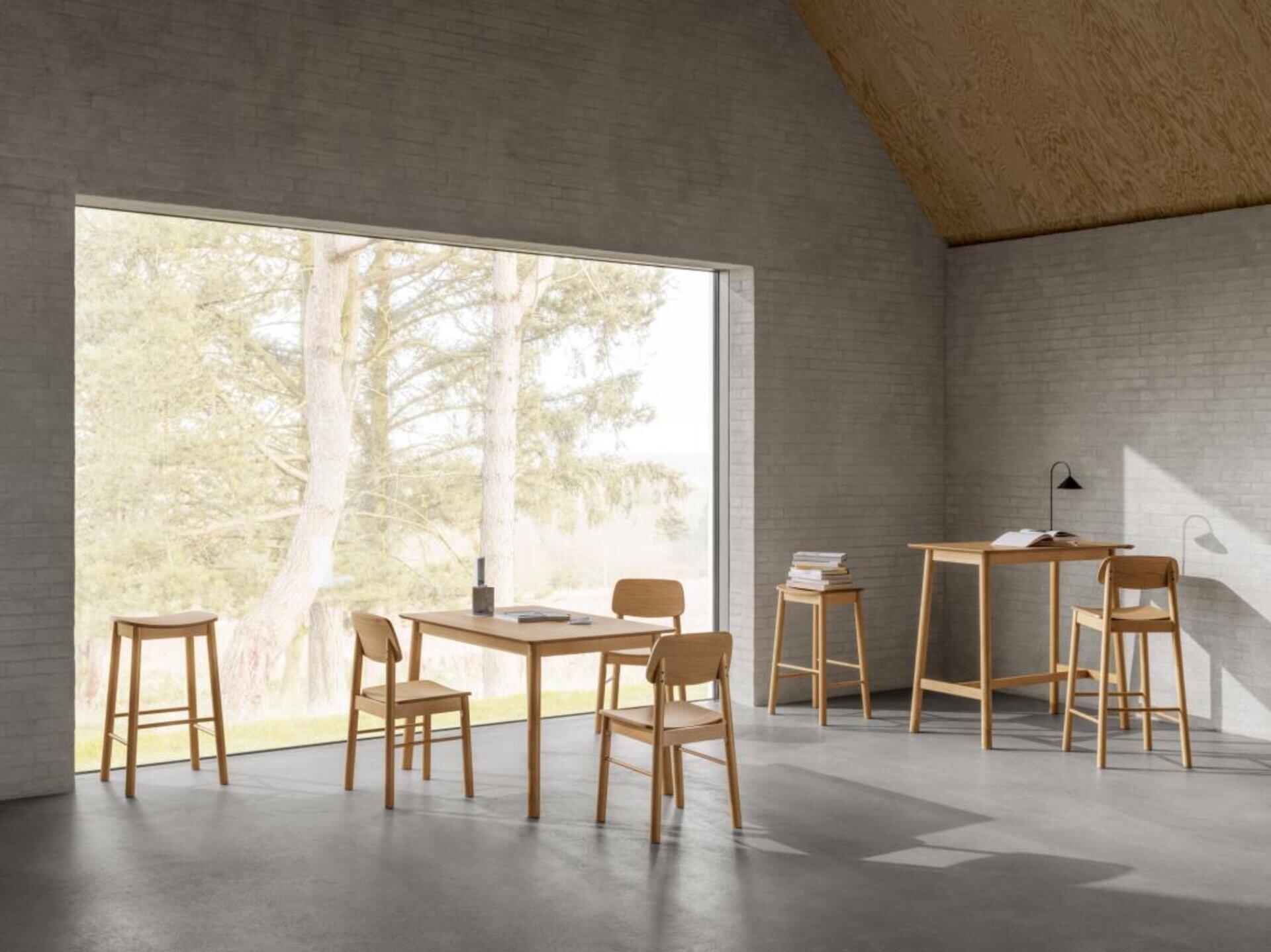Bartisch Barlow mit Fußstütze, platziert in einem minimalistisch eingerichteten Raum mit Blick auf einen Hügel.