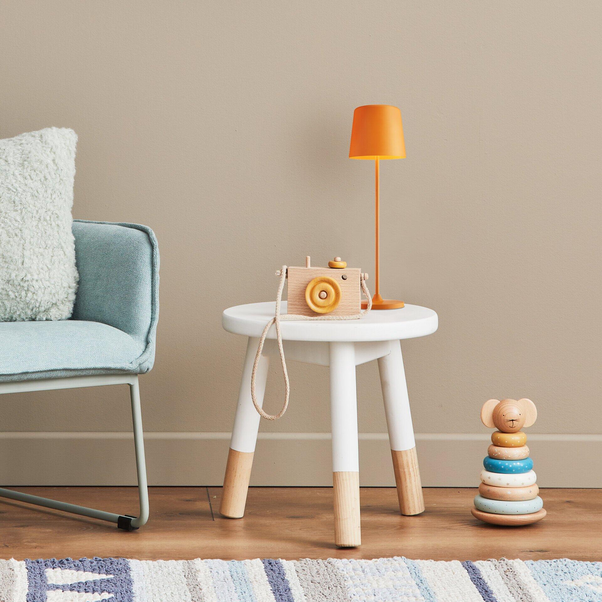 Tischleuchte Kaami in Weiß auf einem Hocker, dargestellt aus erhöhter Perspektive mit umliegenden Accessoires.