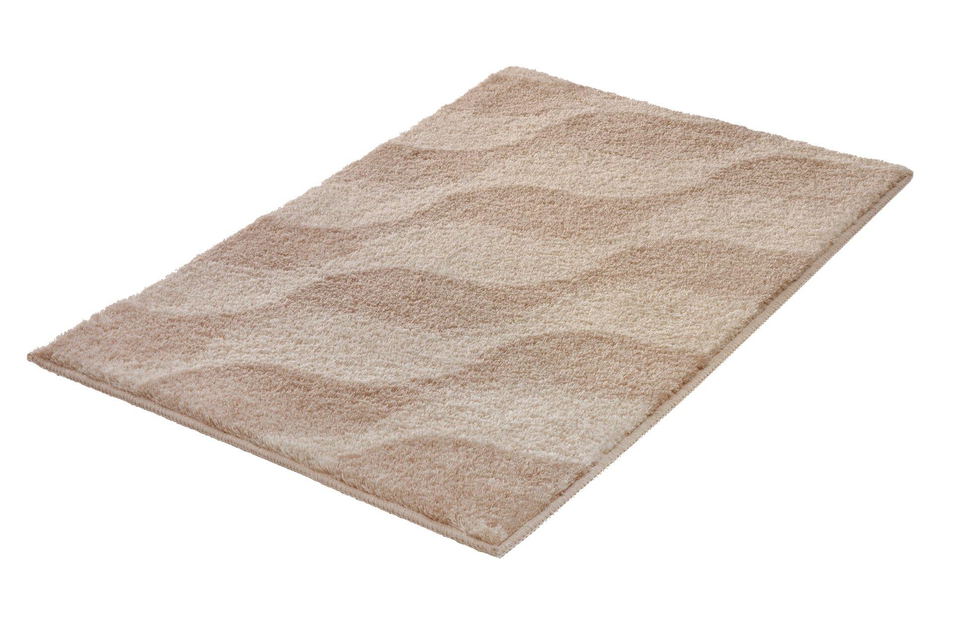 Badteppich Onda in hellem Beige mit wellenartigem Muster und flauschiger Textur.